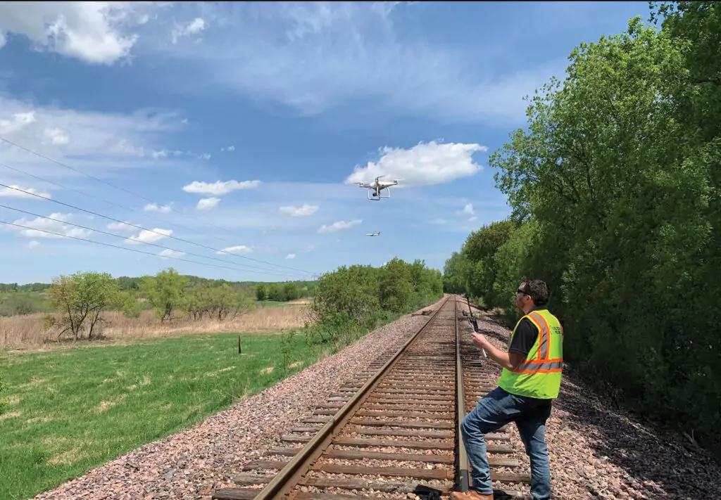 person near railroad tracks with UAV in air