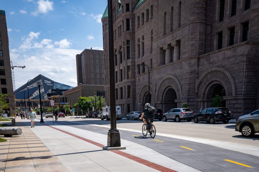 Downtown Minneapolis with US Bank Stadium in background, pedestrians on sidewalk and bike lane