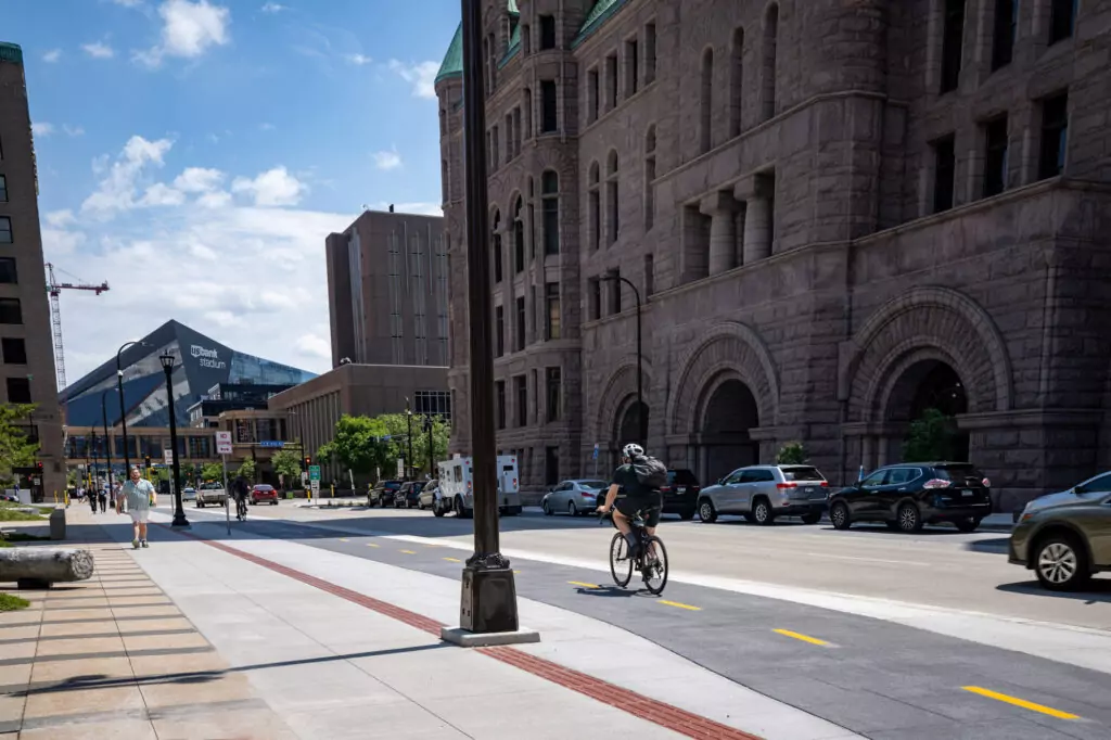 Downtown Minneapolis with US Bank Stadium in background, pedestrians on sidewalk and bike lane