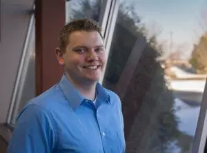 headshot of man in front of window