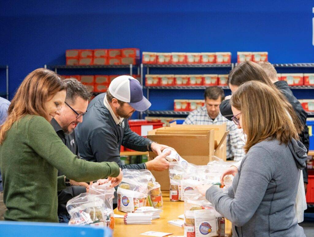 Employees filling bag with food for the Backpack Food Program
