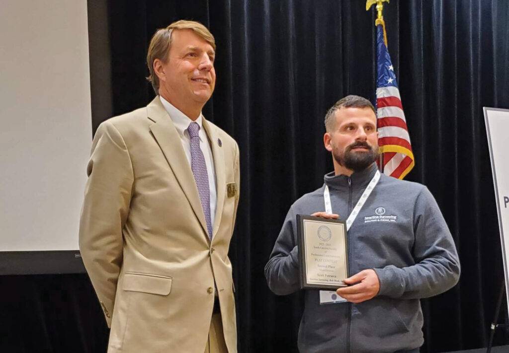 Two men standing at awards ceremony holding a plaque.