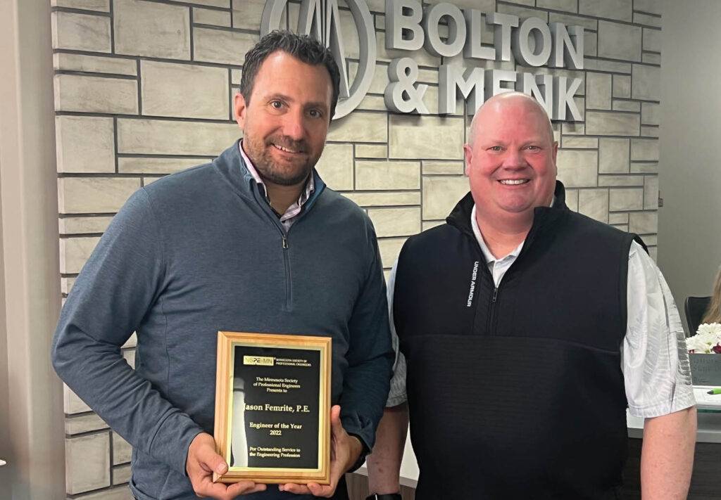 Two men smiling with a plaque