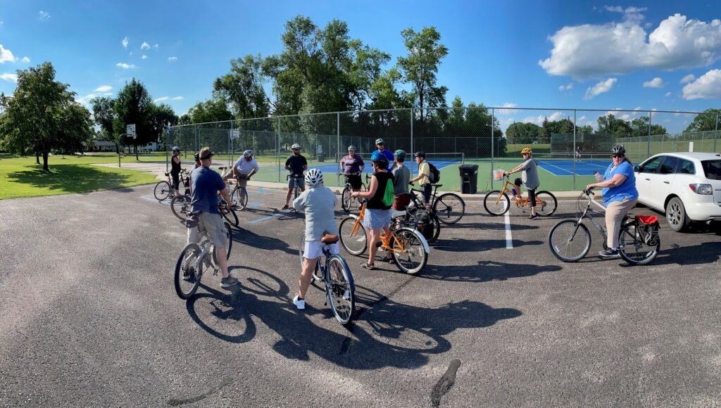 Group of bicyclists next to a park.