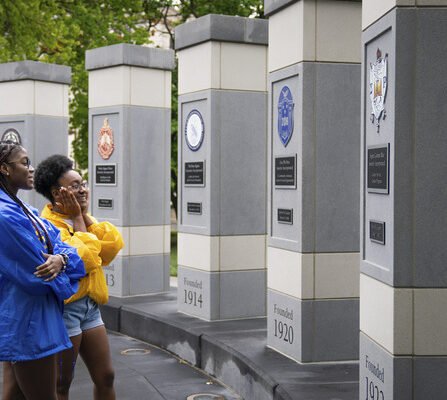 Two people observing a monument with plaques