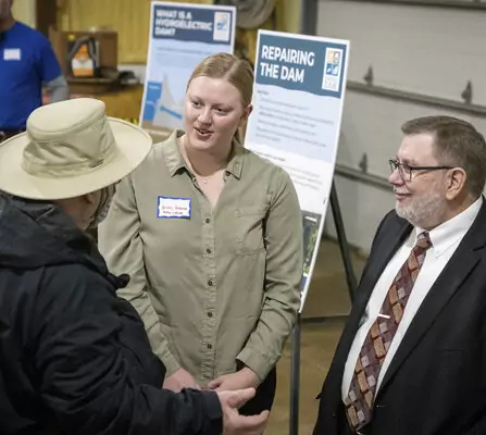 Three people having a discussion with posters in the background