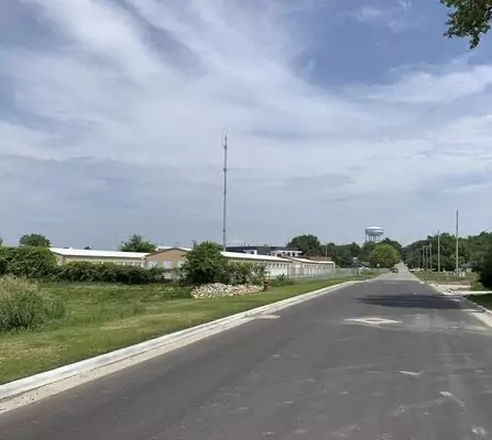 Freshly paved road with buildings and greenery, water tower in the background