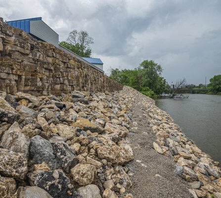 An eco-conscious rock riverbank surrounded by trees and buildings