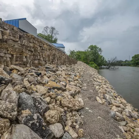 An eco-conscious rock riverbank surrounded by trees and buildings