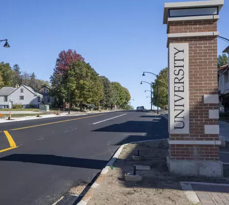 Newly paved street and sidewalk with a monument on display