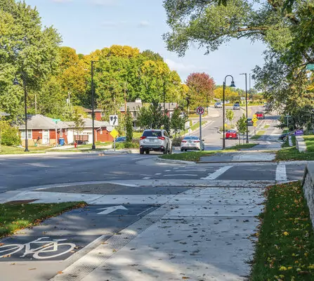 Sidewalk and bike path surrounded by lush greenery and cars passing by