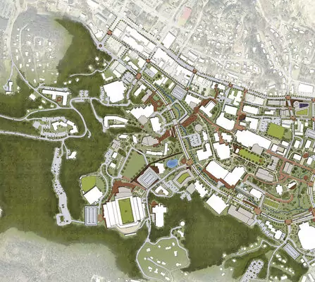 Aerial view of a detailed urban landscape map, featuring various buildings, sports fields, parking lots, and roads. Green areas surround a complex network of streets and structures, indicating a mix of urban and natural spaces.