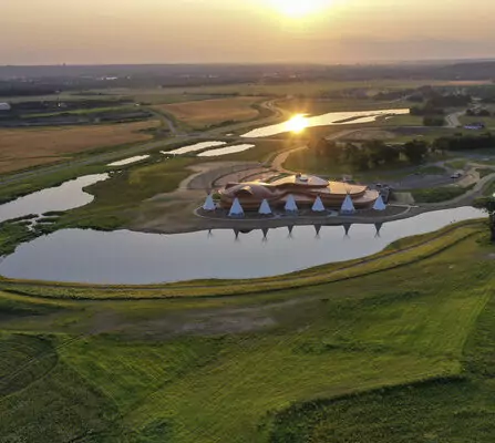A cultural center surrounded by sunset, ponds, and native tepees