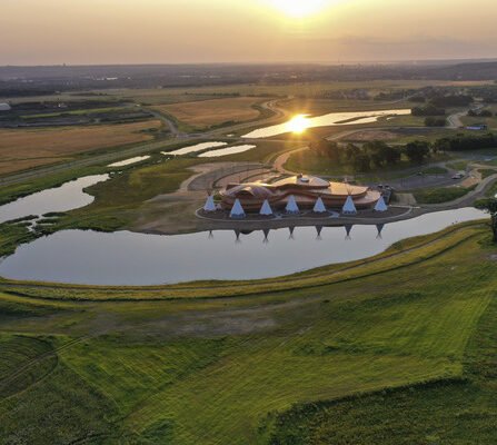 A cultural center surrounded by sunset, ponds, and native tepees