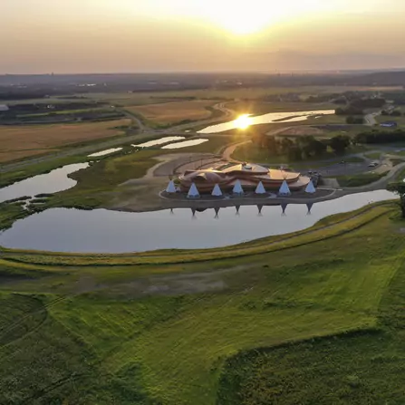 A cultural center surrounded by sunset, ponds, and native tepees
