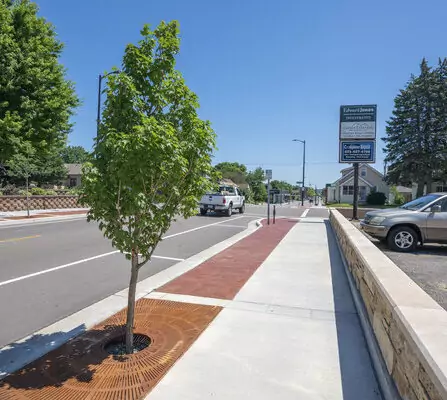 Sidewalk with a tree and brick retaining wall