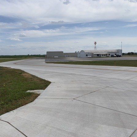 Airport taxiway with hangar in the background.