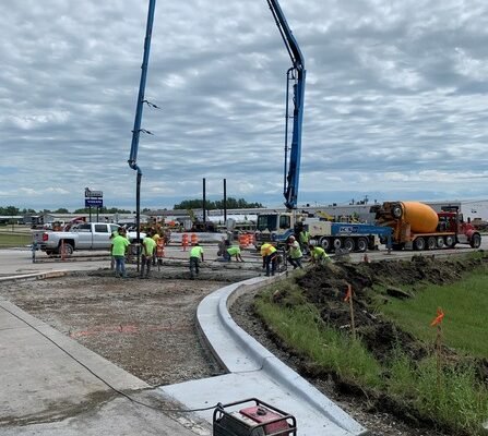 A group of construction workers are pouring concrete from a cement truck at a construction site.