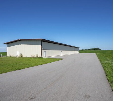 A spacious airport hangar with a concrete lot and lush green surroundings
