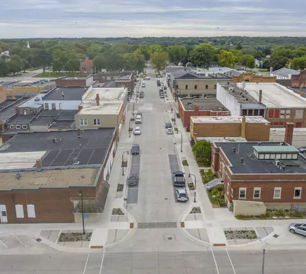 A serene downtown scene with parked cars and buildings lining the side.