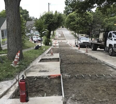 Construction site with torn up road, cones, and construction trucks