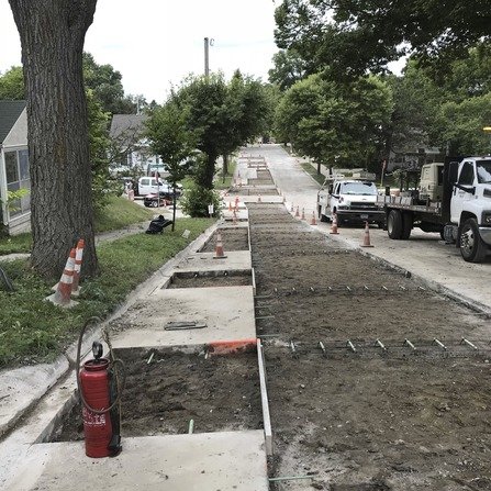 Construction site with torn up road, cones, and construction trucks