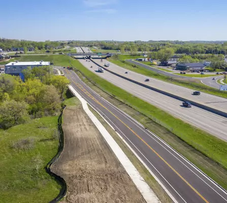 Aerial view of a newly paved road running alongside the busy interstate
