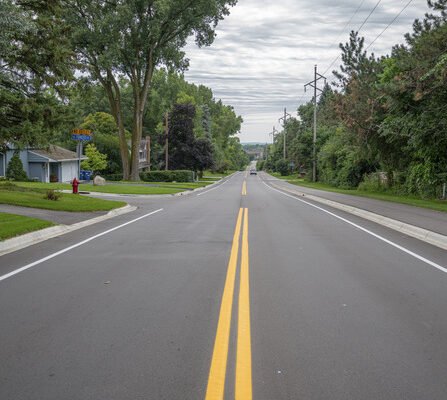 Newly paved road and bike path with brick retaining wall running alongside