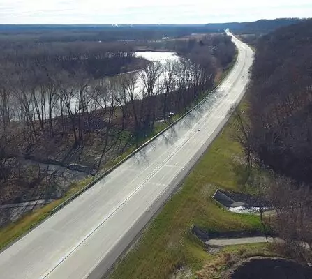 Aerial view of a 4-lane highway cutting through a dense forest