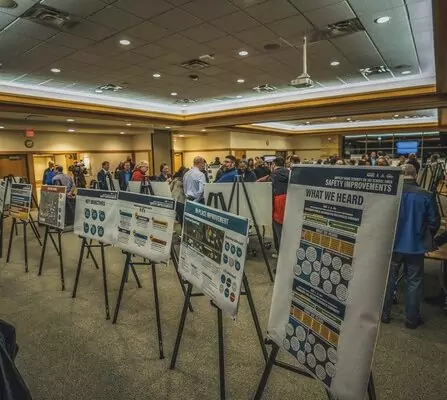 Survey and information boards, attracting a crowd of engaged individuals.