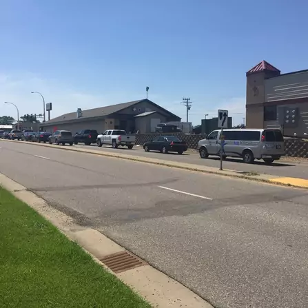 Cars lined up on a road with buildings in the background