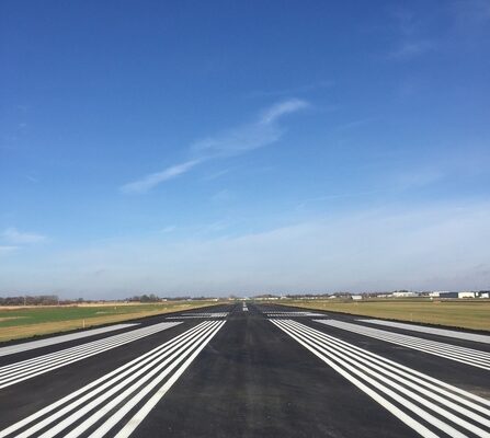 A detailed view of an airport runway, highlighting the white markings on the pavement