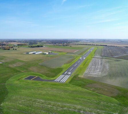 Aerial view of a runway and airport buildings surrounded by fields