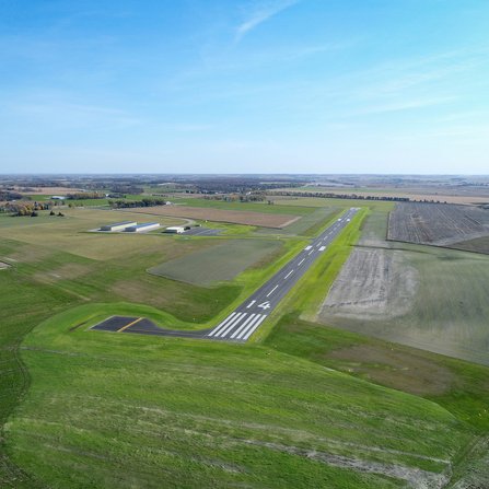 Aerial view of a runway and airport buildings surrounded by fields