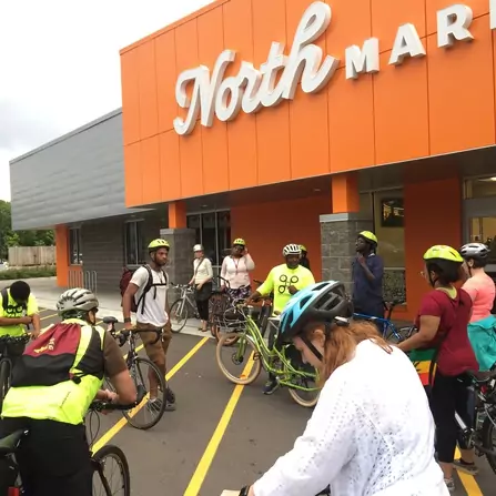 A group of people wearing bright colored shirts riding bicycles together