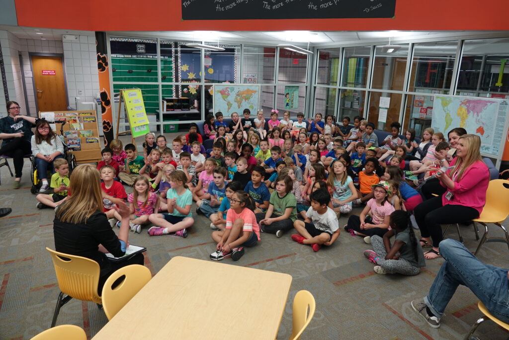 Bolton & Menk employee reading to a classroom of kids sitting on the floor