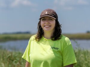 Woman in Bolton & Menk Safety shirt smiling at camera with prairie wetland in the background