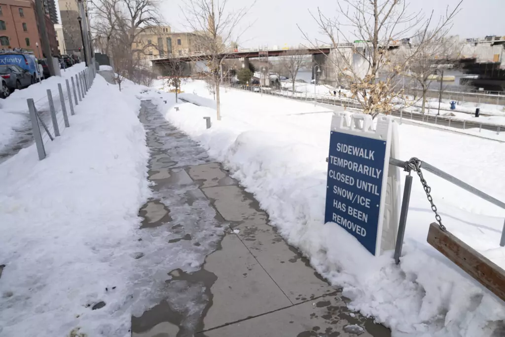 Snow, ice and salt covered sidewalk with snowbanks