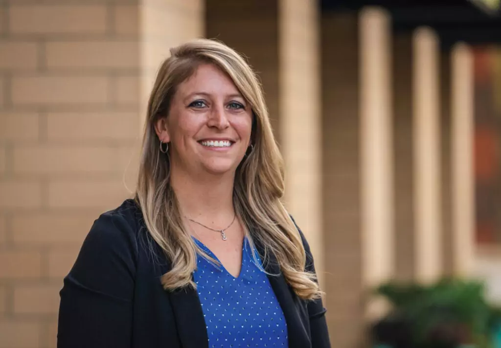 woman in blue shirt and black blazer smiling at camera