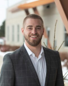 man smiling at camera in white shirt and gray suit jacket