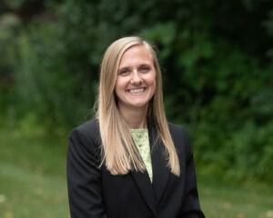 woman in black suit outside smiling at camera