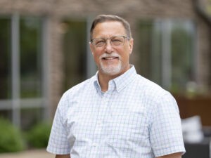 man in white short sleeve button down smiling at camera