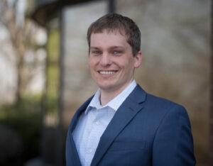 Man in blue suit jacket smiling at camera