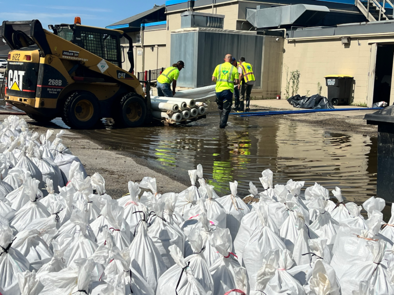 A group of workers creating sandbags in a flooded area