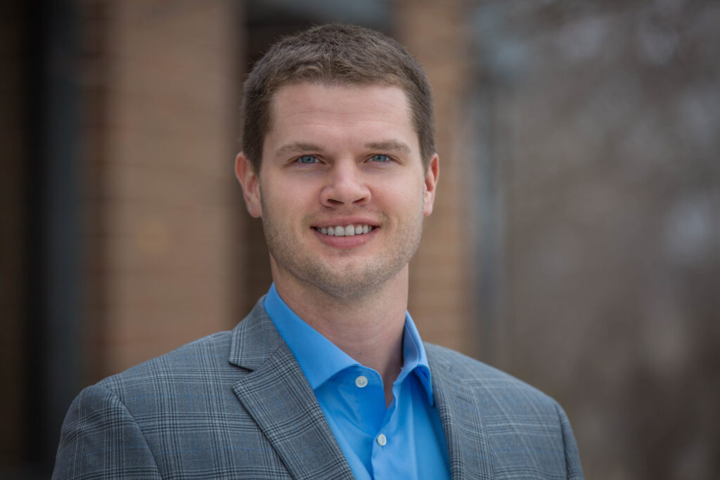 Professional headshot of man wearing blue suit jacket