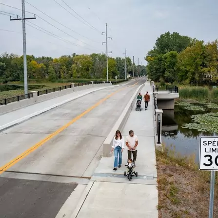 Pedestrians crossing bridge over narrow causeway