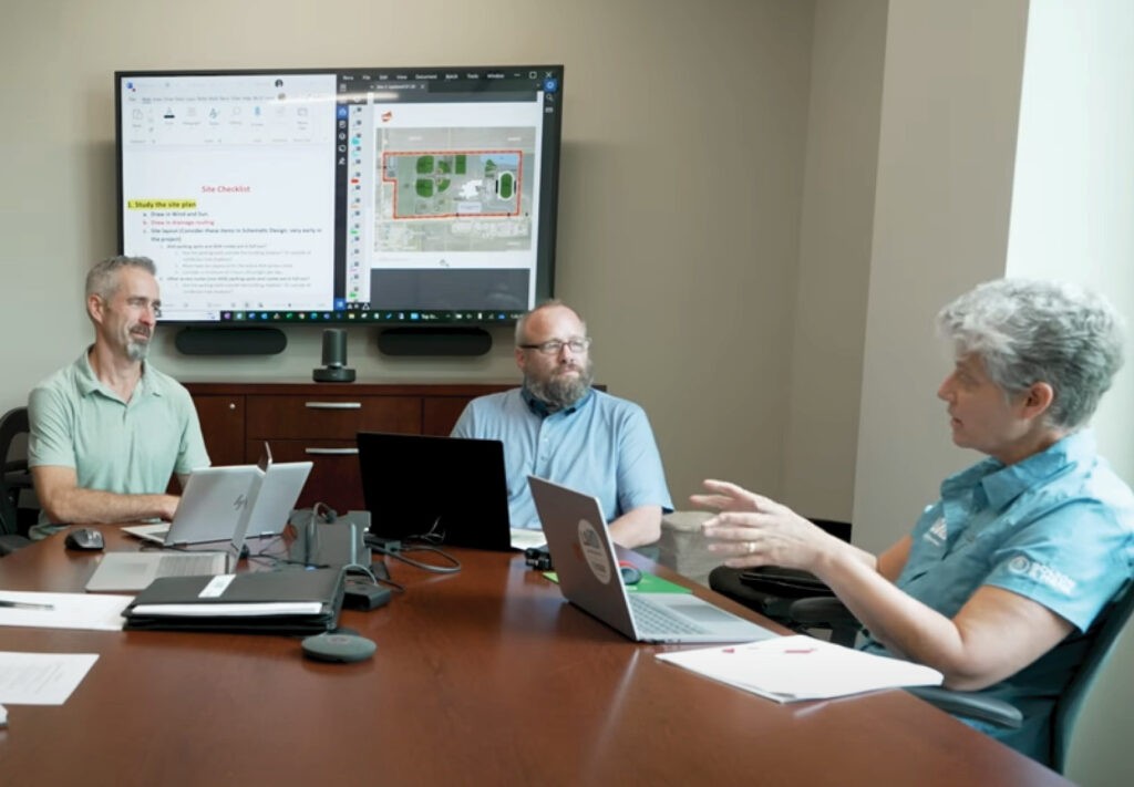 group of people sitting around a table with papers and computers in front of them