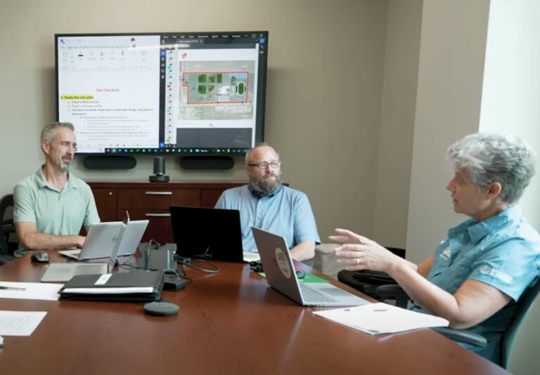 group of people sitting around a table with papers and computers in front of them