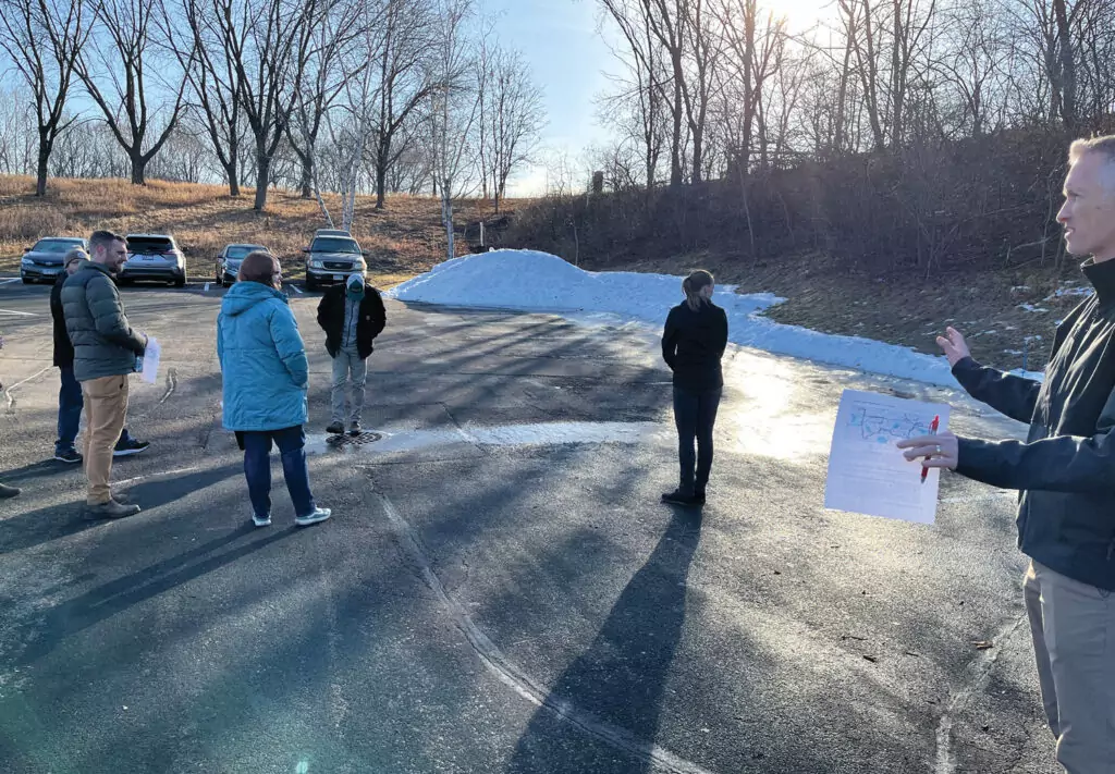 Group of people in a parking lot looking at snowmelt