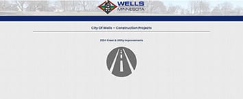 The website screenshot showcases the Wells, Minnesota logo at the top. It reads City Of Wells - Public Projects, with a subtitle 2024 Street & Utility Improvements. An icon of a road appears below, set against a faint rural scene.